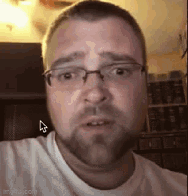 a man with glasses and a beard is looking at the camera .