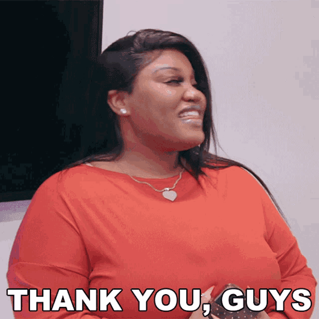 a woman in a red shirt is smiling and says thank you guys