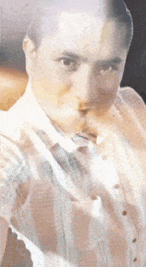a man in a striped shirt and tie is looking at the camera .
