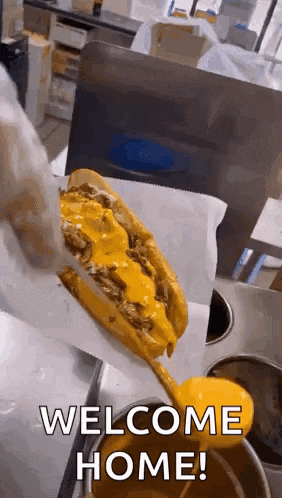 a cheeseburger is being poured on a bun with the words `` welcome home '' written on it .