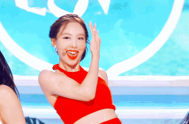 a woman in a red crop top is smiling and dancing