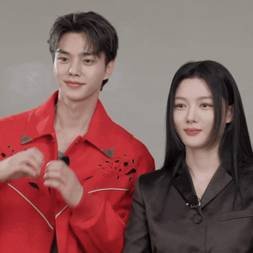 a man in a red jacket and a woman in a black jacket are standing next to each other