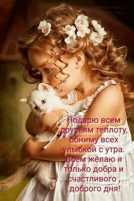 a little girl is holding a white kitten in her arms
