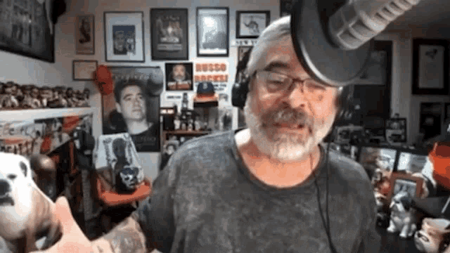 a man wearing headphones stands in front of a microphone in a room with posters on the wall that say queso rocks