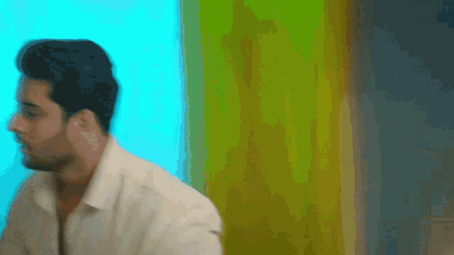 a man in a white shirt is standing in front of a yellow and blue wall
