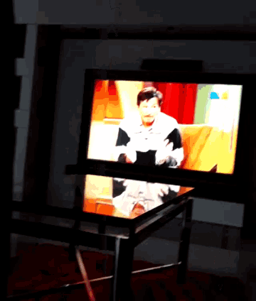 a tv screen shows a man sitting on a couch talking