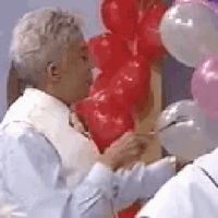 a man is holding a bunch of red and pink balloons in his hands .