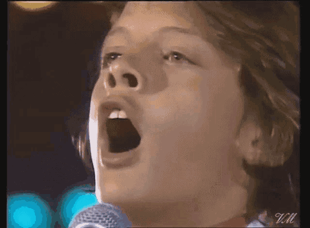 a close up of a person singing into a microphone .