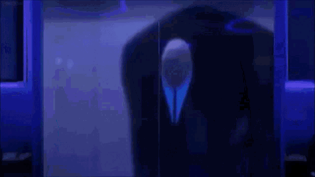 a man in a suit and tie is standing in a dark room .