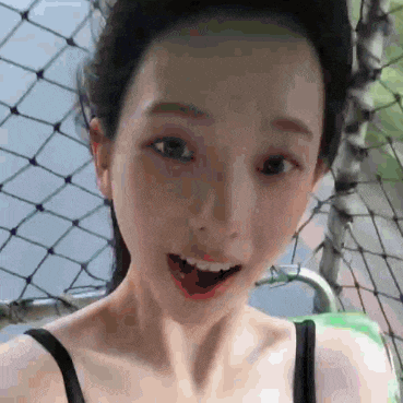 a close up of a woman 's face with her mouth open and a fence in the background