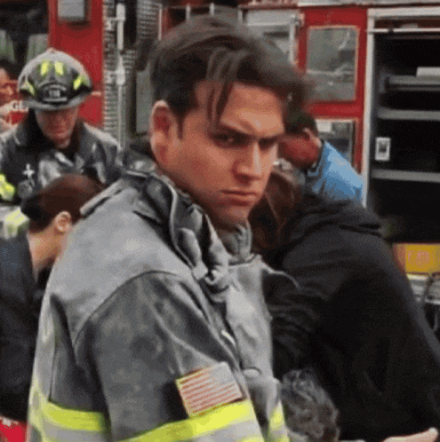 a man in a fireman 's uniform stands in front of a fire truck