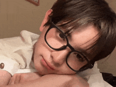 a close up of a person wearing glasses and a white shirt