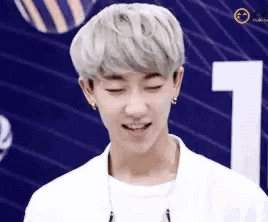 a young man with white hair is smiling in front of a number one