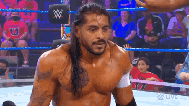 a wrestler is standing in a wrestling ring with a crowd watching .