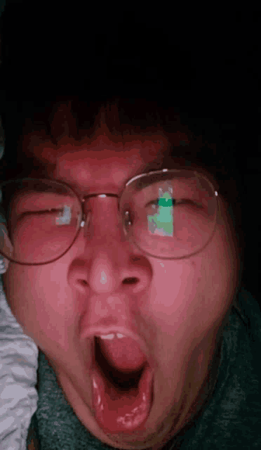 a man wearing glasses is yawning with his eyes closed
