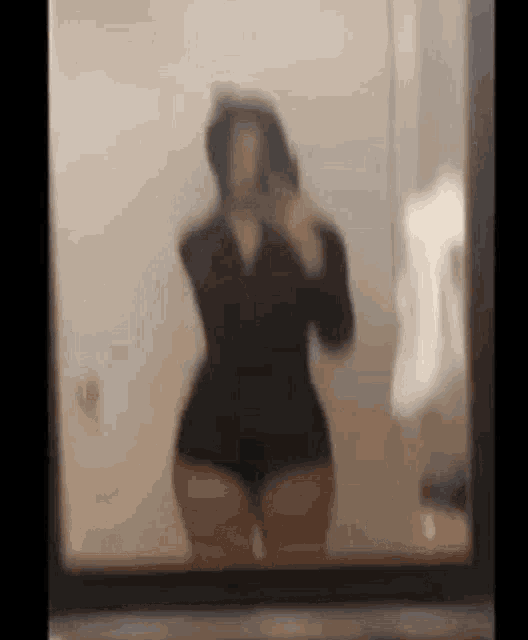 a woman is taking a selfie in front of a mirror in a bathroom .