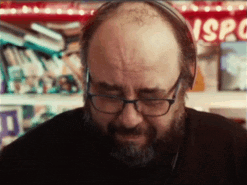 a bald man with glasses and a beard is wearing headphones .