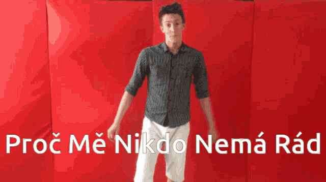 a man stands in front of a red wall with the words proč me nikdo nema rad written on it