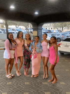 a group of women are posing for a picture in front of a white car