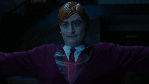 a man with red hair and a purple shirt is standing in a dark room