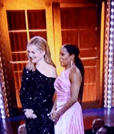 two women are standing next to each other on a stage .