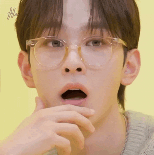 a close up of a young man wearing glasses with his mouth open .