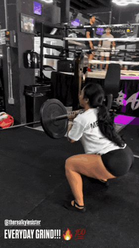 a woman squatting down with a barbell in a gym