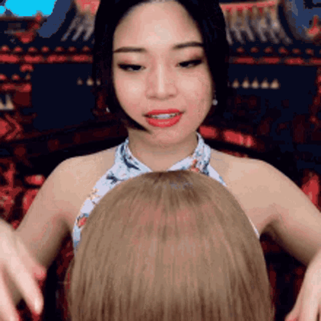 a woman in a halter top is hugging another woman 's head .