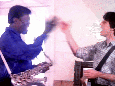 a man in a blue shirt is playing a saxophone next to another man