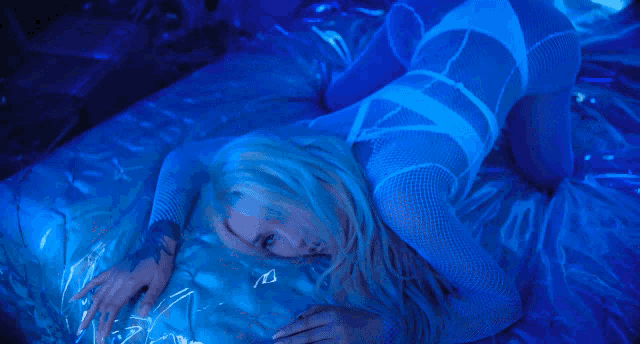 a woman laying on a bed with a blue light behind her