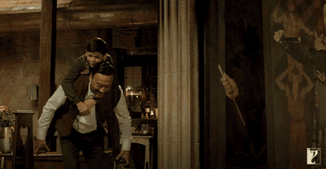 a man is carrying a little boy on his shoulders with the letter p on the bottom left