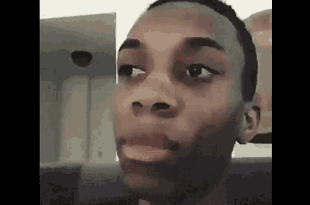 a young man is sitting on a couch with his mouth open and making a funny face .