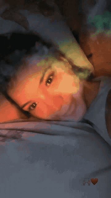 a close up of a woman laying on a bed with two hearts on the bottom right