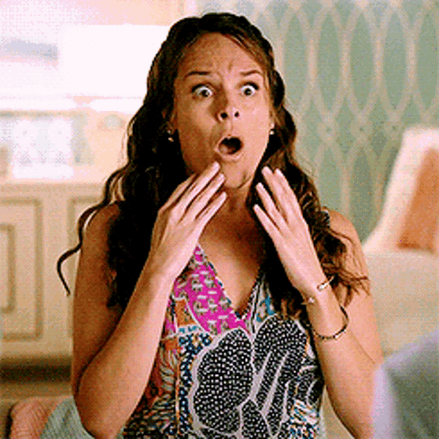 a woman with a surprised look on her face wearing a colorful top
