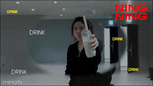 a woman is holding a glass of milk with a straw in front of a sign that says drink