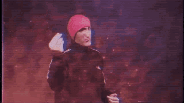 a man wearing a pink hat and a black jacket is making a funny face
