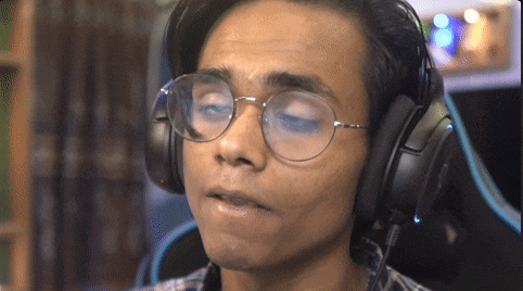 a man wearing headphones and glasses looks at the camera with his eyes closed
