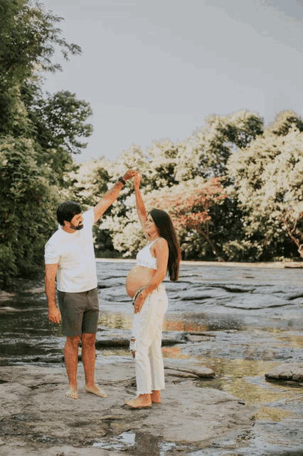 a man and a pregnant woman are dancing in the water