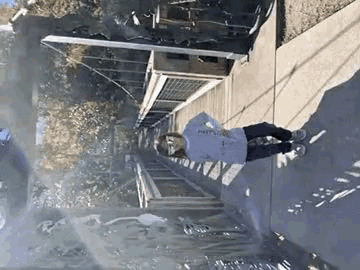a person is walking down a sidewalk with a reflection of trees in the water .