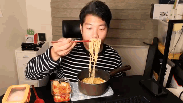a man in a striped shirt eats noodles with chopsticks