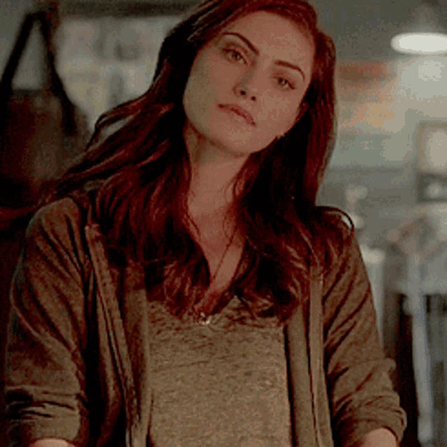a woman with long brown hair is wearing a gray sweater