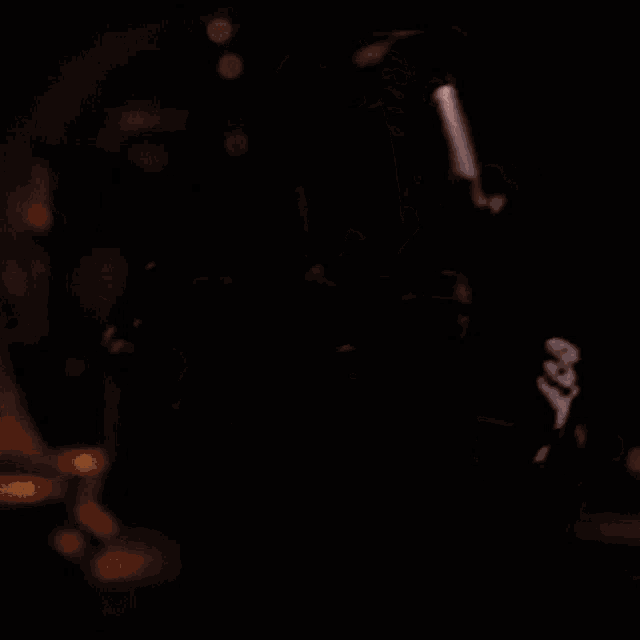 a man wearing a welding mask is welding a piece of metal in a dark room .