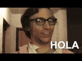 a man wearing glasses and a pink shirt is smiling with the word hola above him