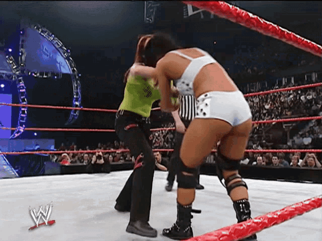 two women are wrestling in a wrestling ring with a w logo on the bottom