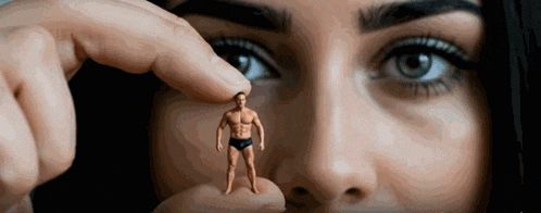 a woman is holding a small figure of a man between her fingers