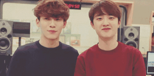 two young men are standing next to each other in front of a sign that says ' s.m.p.s. '