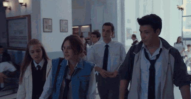 a group of students walking down a hallway with a bee on the wall