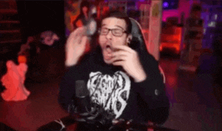 a man wearing glasses is sitting in front of a microphone and eating something .
