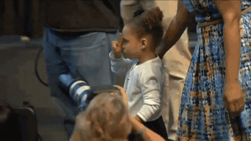 a little girl in a white shirt is being held by a woman in a blue dress