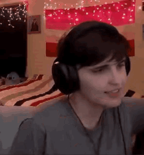 a woman wearing headphones is sitting in front of a bed in a room .